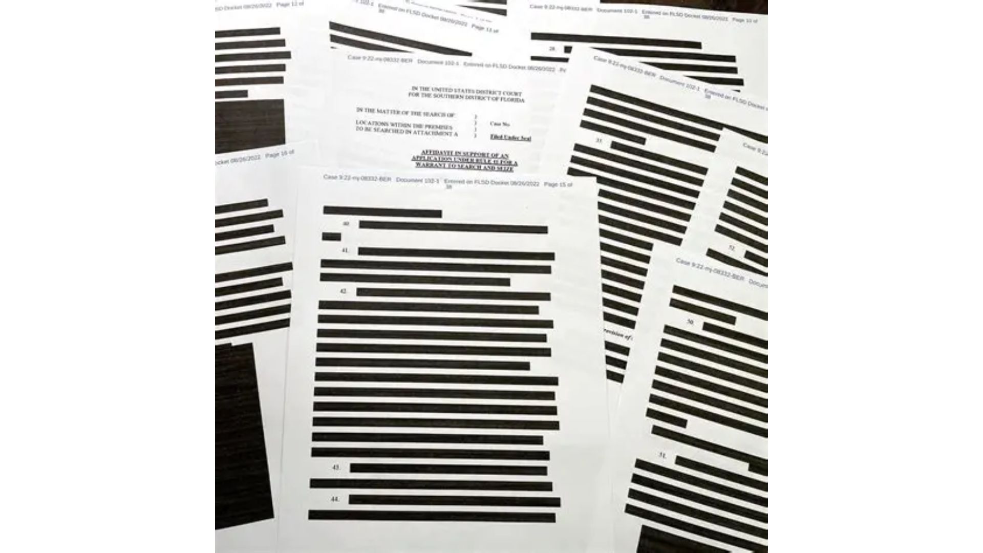 A pile of court documents with most of the text blacked out by redaction bars — visualising disagreement and information that gets hidden before you see it.